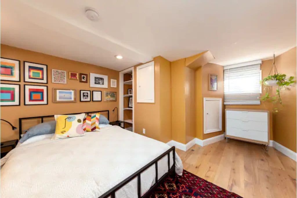 The guest bedroom in the basement is very spacious and filled with art.